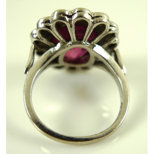 839 - An 18ct white gold, diamond and ruby ring, the central oval cut stone of over 3ct, 12 by 10mm, encir... 