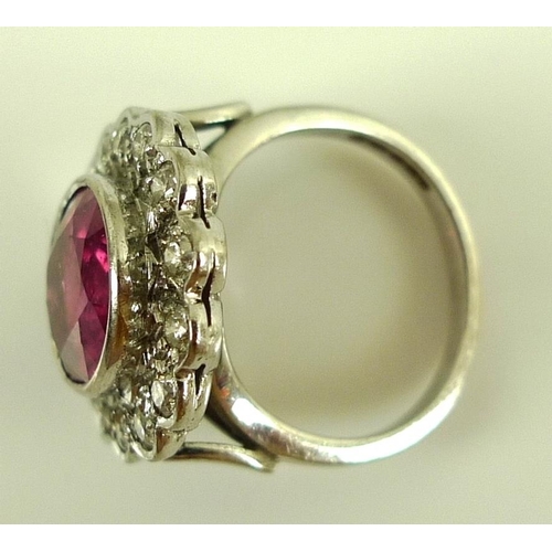 839 - An 18ct white gold, diamond and ruby ring, the central oval cut stone of over 3ct, 12 by 10mm, encir... 