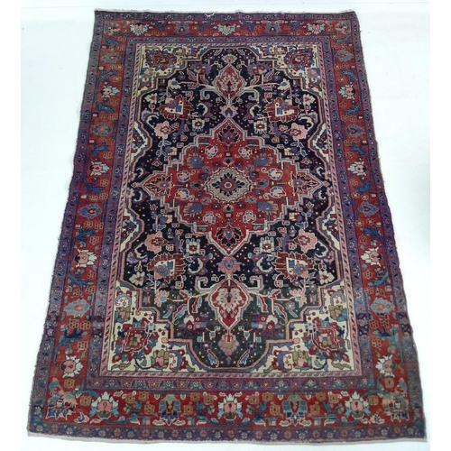 859A - A hand woven Persian rug, main border having Herati design enclosing a blue ground field with red me... 