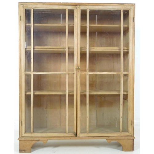 863A - A Victorian pine glazed bookcase, twin glazed doors with brass knob, three fixed shelves, raised on ... 