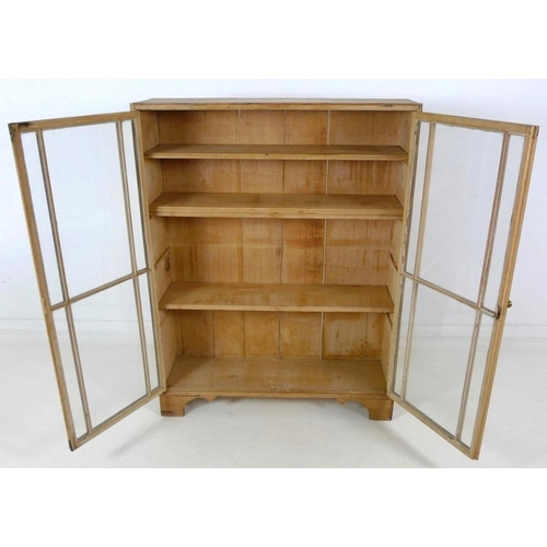 863A - A Victorian pine glazed bookcase, twin glazed doors with brass knob, three fixed shelves, raised on ... 