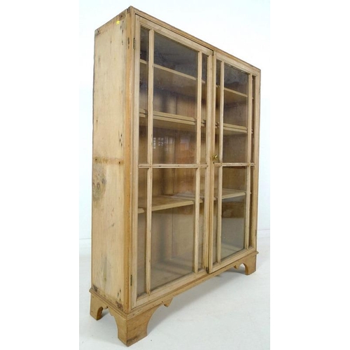 863A - A Victorian pine glazed bookcase, twin glazed doors with brass knob, three fixed shelves, raised on ... 