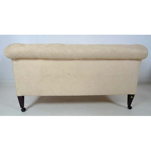 873 - An Edwardian drop end two seater settee, upholstered in cream foliate fabric, raised on square secti... 