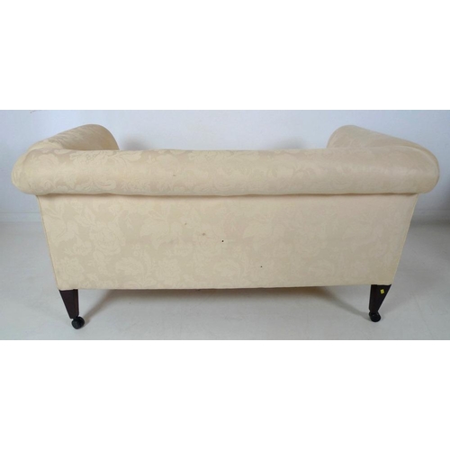 873 - An Edwardian drop end two seater settee, upholstered in cream foliate fabric, raised on square secti... 