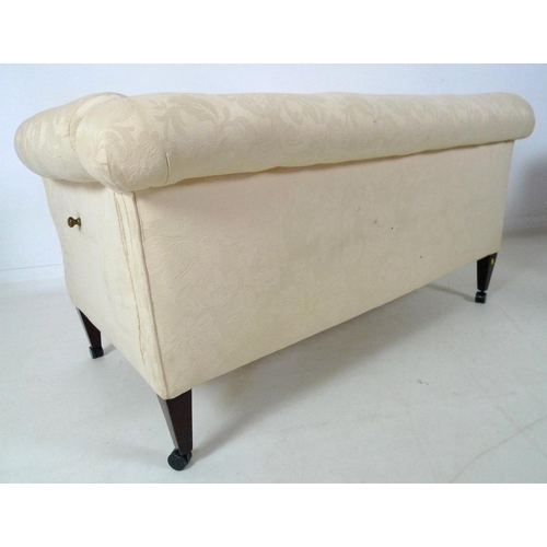 873 - An Edwardian drop end two seater settee, upholstered in cream foliate fabric, raised on square secti... 