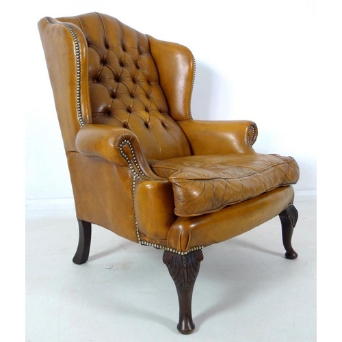 876 - A Georgian style tan button back leather arm chair, scroll over arms, brass tacks, carved front supp... 