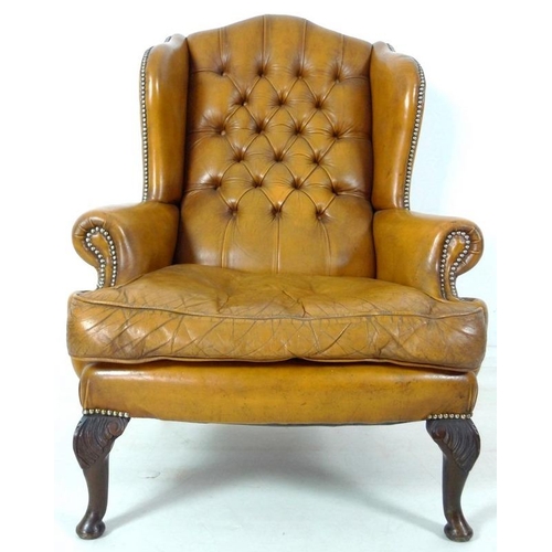 876 - A Georgian style tan button back leather arm chair, scroll over arms, brass tacks, carved front supp... 