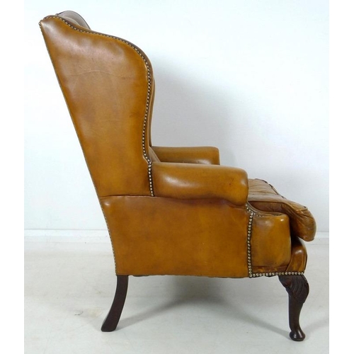 876 - A Georgian style tan button back leather arm chair, scroll over arms, brass tacks, carved front supp... 