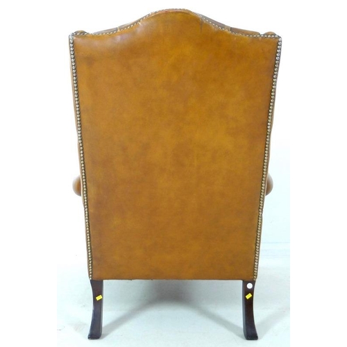 876 - A Georgian style tan button back leather arm chair, scroll over arms, brass tacks, carved front supp... 