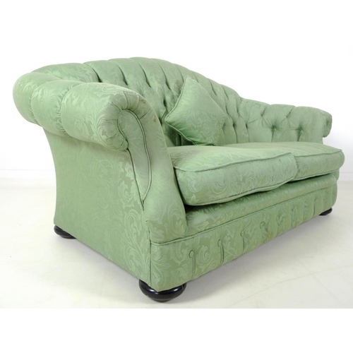 882 - A Victorian style two seater settee, with arched button back, scroll arms and flattened bun feet, up... 