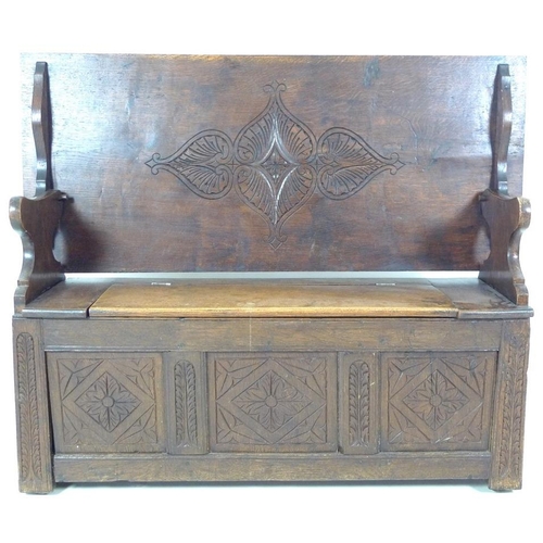 888 - A Victorian oak monk's bench, three panel front carved with floral and foliate motif, lift lid seat,... 