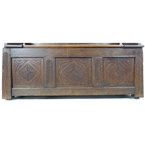 888 - A Victorian oak monk's bench, three panel front carved with floral and foliate motif, lift lid seat,... 