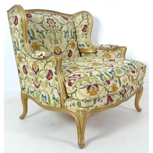 889 - A French carved wood wing armchair, in 19th century style, with gold coloured painted frame,  cream ... 