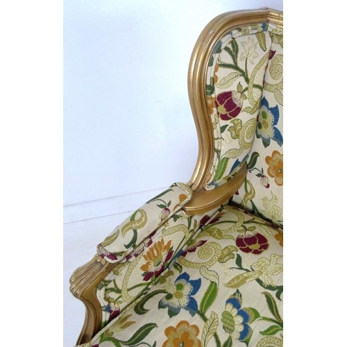 889 - A French carved wood wing armchair, in 19th century style, with gold coloured painted frame,  cream ... 