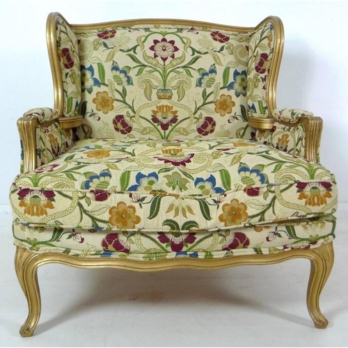 889 - A French carved wood wing armchair, in 19th century style, with gold coloured painted frame,  cream ... 