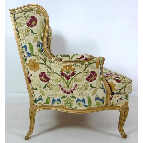 889 - A French carved wood wing armchair, in 19th century style, with gold coloured painted frame,  cream ... 