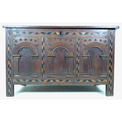 1006 - An 18th century oak coffer or blanket box, inlaid with chevron detailing, three arched panels to the... 