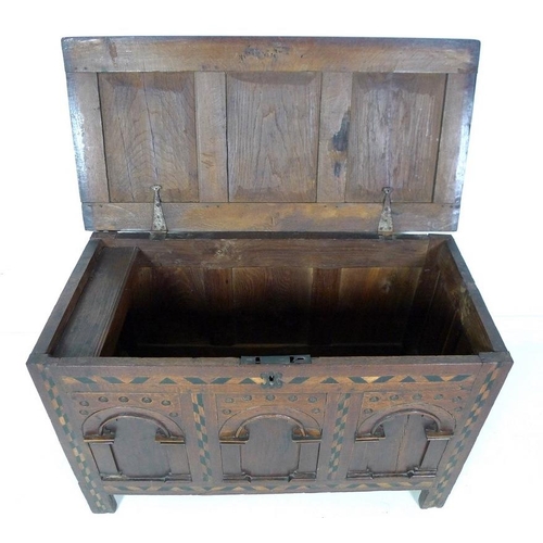 1006 - An 18th century oak coffer or blanket box, inlaid with chevron detailing, three arched panels to the... 