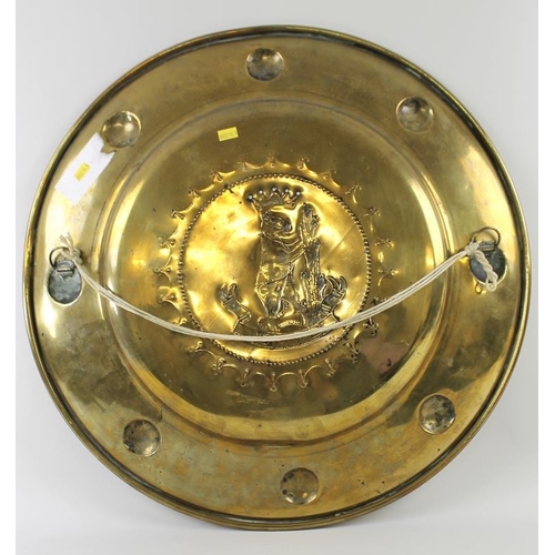 705 - A 19th century brass charger, embossed with the Warwick coat of arms, 55cm diameter.