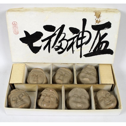 786 - A set of seven Japanese sake cups, the bases of each moulded as the faces of the Seven Lucky Gods or... 