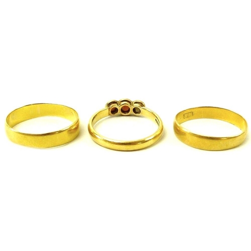 839 - A group of three 22ct gold rings, comprising two wedding bands, size K, and size L, and a three ston... 