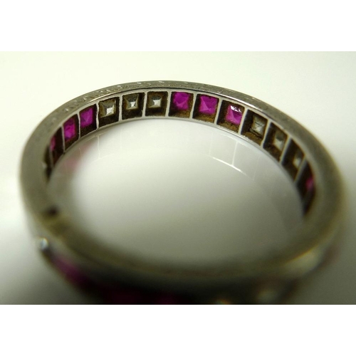 845 - A white gold, ruby and diamond eternity ring, the scroll engraved band set with twelve emerald cut d... 