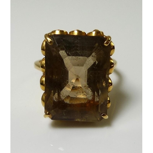 855 - An 18ct gold dress ring set with large smoky quartz, the emerald cut stone 17.5 by 12.3 by 9.8mm, ba... 