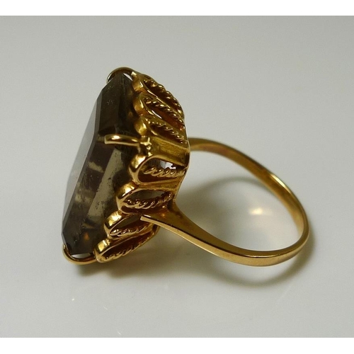 855 - An 18ct gold dress ring set with large smoky quartz, the emerald cut stone 17.5 by 12.3 by 9.8mm, ba... 