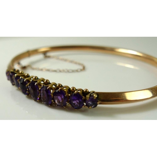 876 - A Victorian rose gold bangle set with nine oval cut amethysts, largest stone 6.3 by 3.5mm, one stone... 