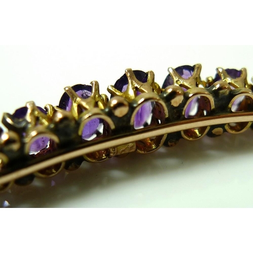 876 - A Victorian rose gold bangle set with nine oval cut amethysts, largest stone 6.3 by 3.5mm, one stone... 