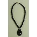 A Whitby jet necklace, the tear drop shaped pendant relief carved with a lady's head in profile and ... 