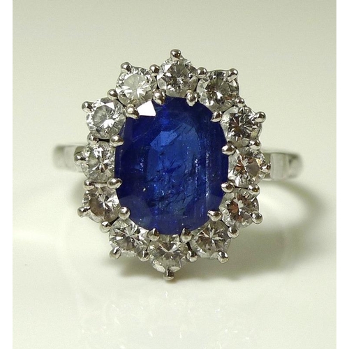 900 - An 18ct white gold, sapphire and diamond ring, the large dark cornflower blue oval sapphire 8mm by 7... 