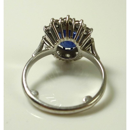 900 - An 18ct white gold, sapphire and diamond ring, the large dark cornflower blue oval sapphire 8mm by 7... 