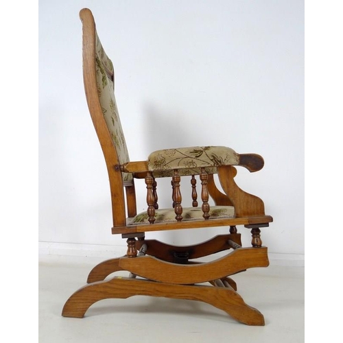 911 - A mid 20th century oak framed rocking chair, sprung rocking base, turned spindles to padded arms, up... 