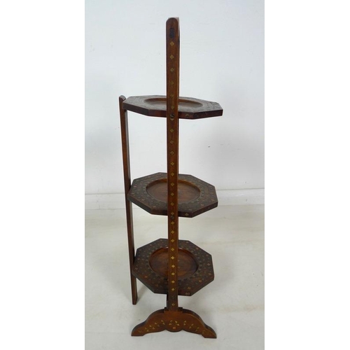 919 - An Aesthetic design mahogany three tier cake stand, inlaid with brass and enamelled, 25.5 by 77.5cm ... 