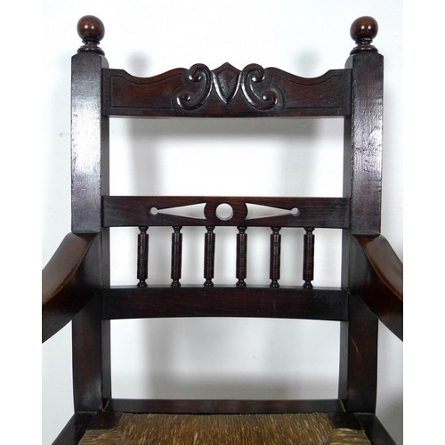 935 - A late 19th century stained oak open armchair, carved crest to the top rail , drop in rush seats, ri... 