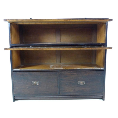 941 - A mid 20th century stained oak bookcase, with two full width slide and hide leaded glass doors, over... 