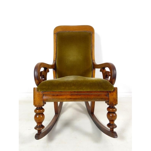 952 - A Victorian mahogany rocking chair, with shaped rail, scroll open arms, and turned front legs, uphol... 