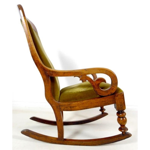 952 - A Victorian mahogany rocking chair, with shaped rail, scroll open arms, and turned front legs, uphol... 