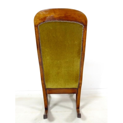 952 - A Victorian mahogany rocking chair, with shaped rail, scroll open arms, and turned front legs, uphol... 