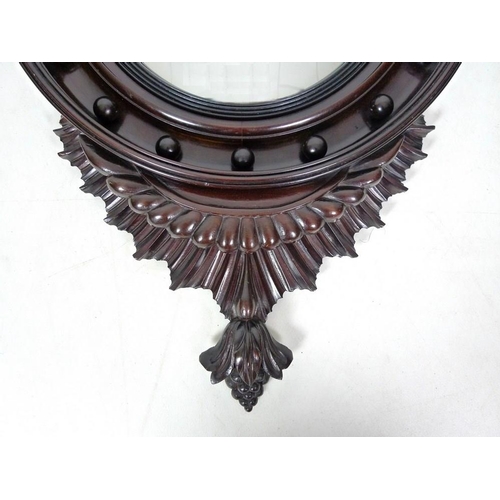 959 - A reproduction porthole mirror, the convex glass in carved stained frame with eagle finial, 46.5 by ... 