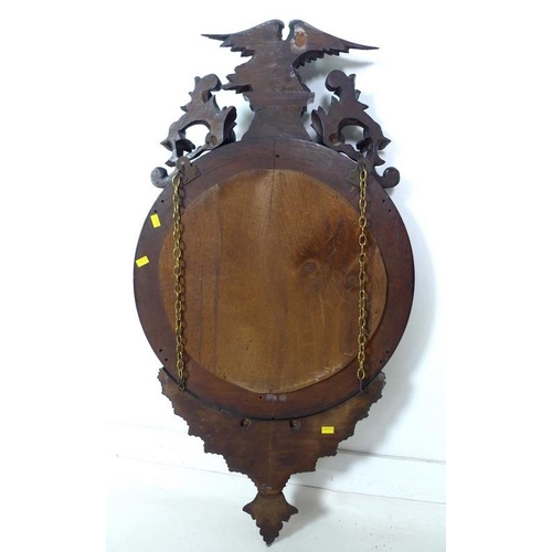 959 - A reproduction porthole mirror, the convex glass in carved stained frame with eagle finial, 46.5 by ... 