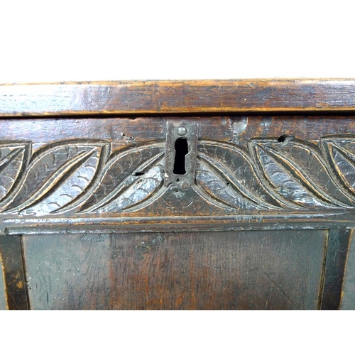 986 - An early 18th century oak coffer, three panel front with a carved frieze of leaves, lift lid with ca... 