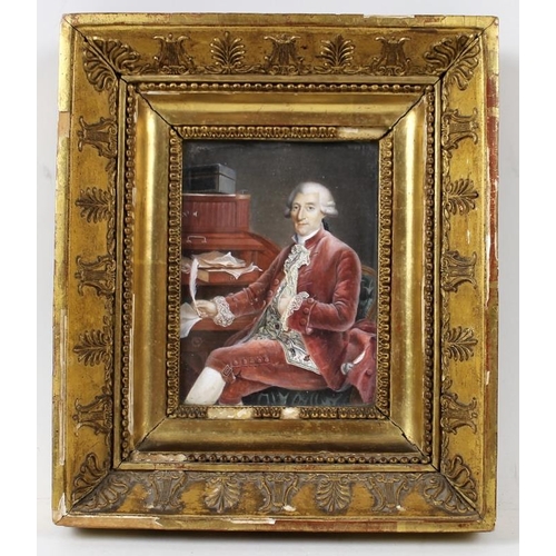 629 - An 18th century portrait miniature of a seated gentleman in a red velvet suit beside his desk, weari... 