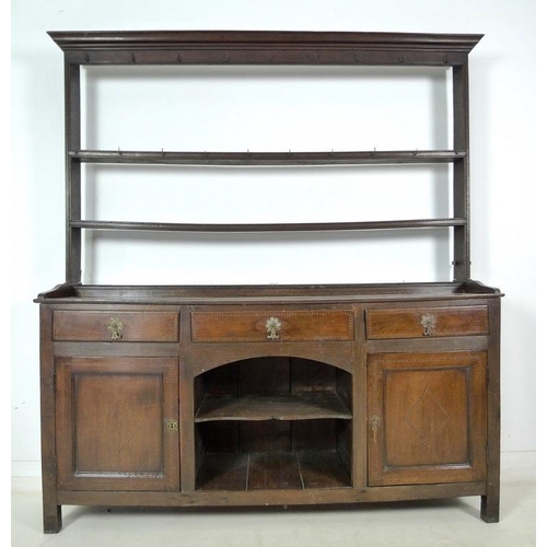 933 - A Georgian oak and inlaid dresser, two shelf plate rack, the base with three frieze drawers, cast br... 