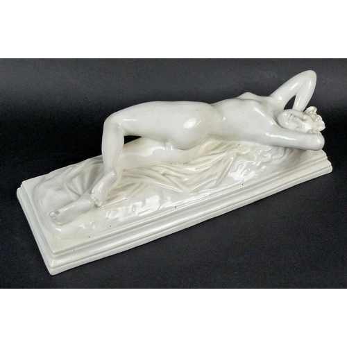 503 - A mid 19th century reclining nude female figure, stretching upon a rumpled sheet above a stepped rec... 