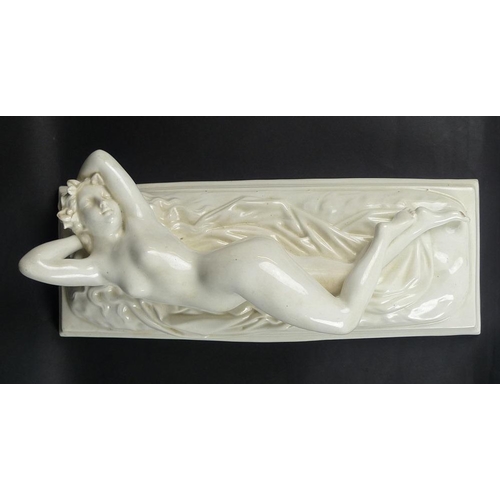 503 - A mid 19th century reclining nude female figure, stretching upon a rumpled sheet above a stepped rec... 