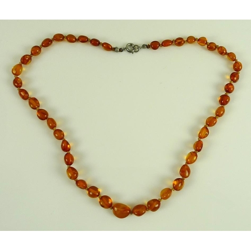 901 - An amber bead necklace, the oval beads each approximately 8mm with larger central bead of 11mm, whit... 