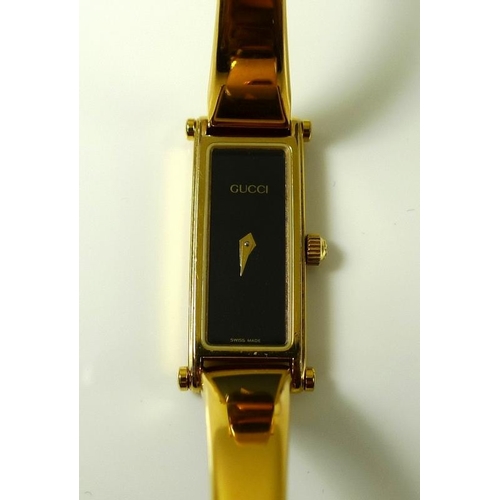 905 - A lady's vintage classic Gucci watch, with sniffle clasp to a hinged bracelet strap, Gucci emblem an... 