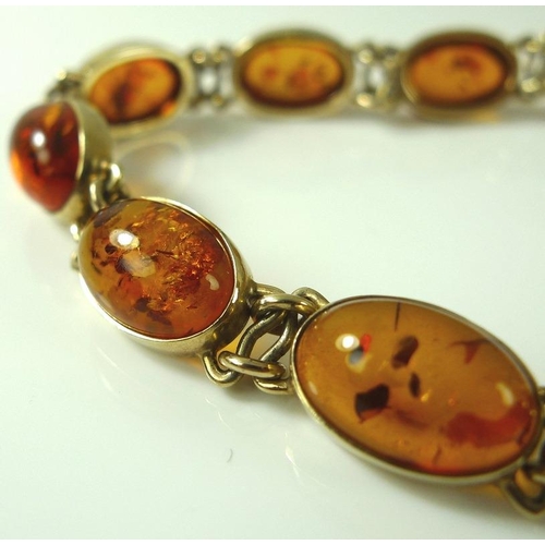 913 - A 9ct gold and amber bracelet, comprised of eleven oval amber cabochons, on gold link setting, 13.4g... 